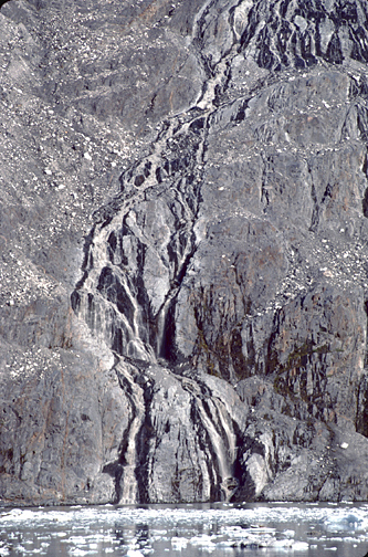 waterfall down a rock face to icebergs in water