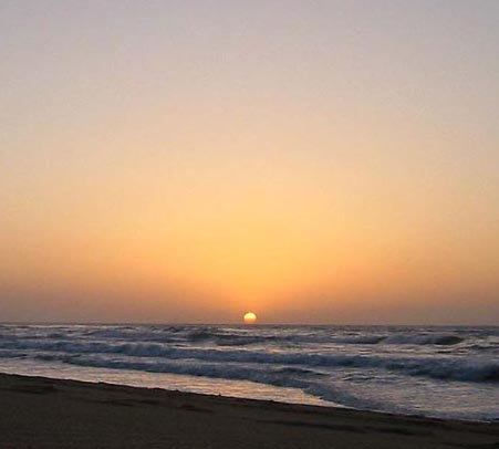 orange sun low touching the blue black water at sunset