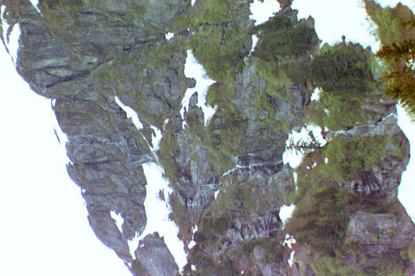 small waterfall in side of mountain with snow